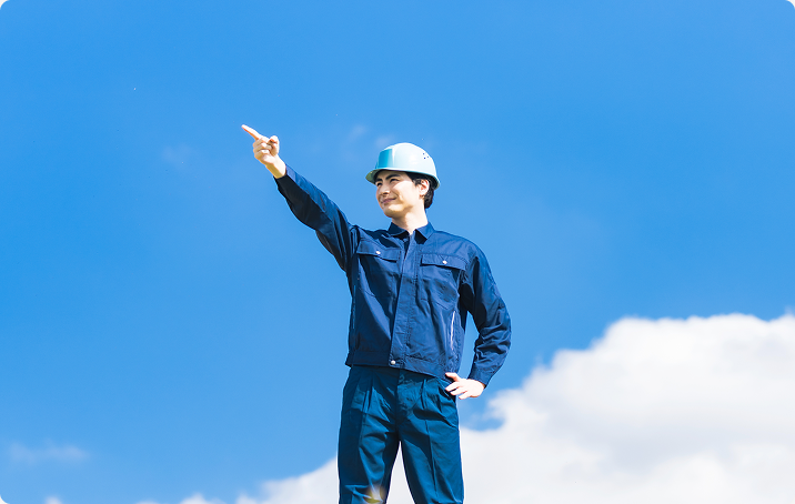 青空の下で立つ作業着の男性